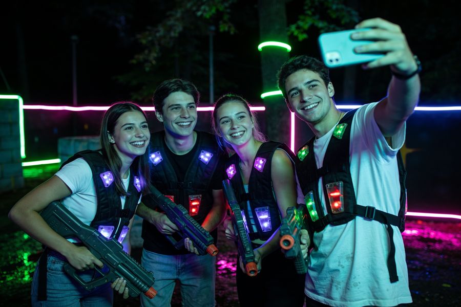 Group of friends taking a selfie in laser tag gear after a match, neon lights behind them